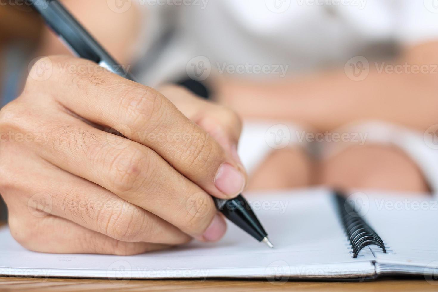 donna d'affari che scrive qualcosa sul taccuino in ufficio o in un bar, mano di donna che tiene penna con firma sul rapporto cartaceo. concetti di affari foto