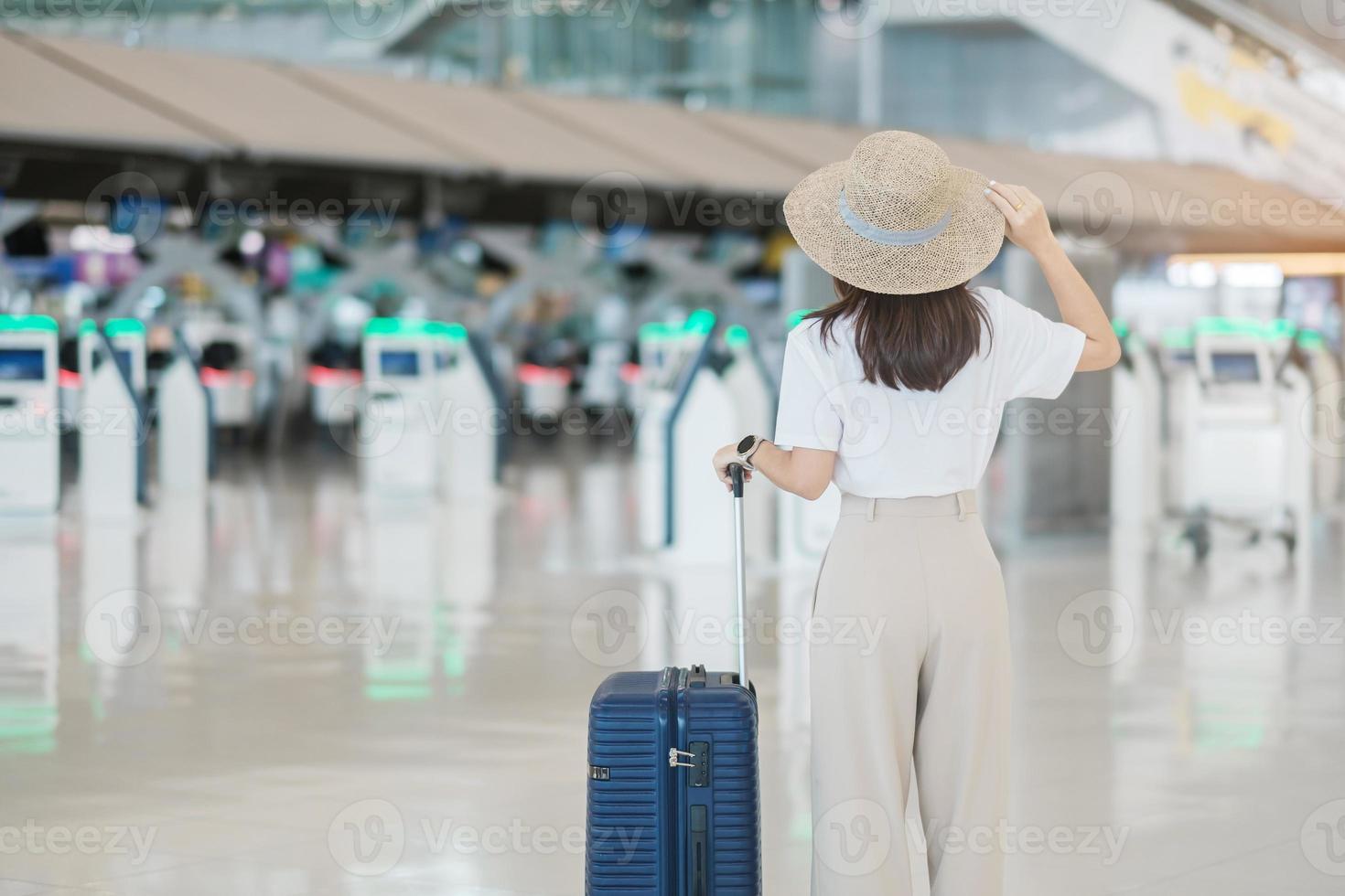 maniglia del bagaglio della holding della mano della giovane donna prima di controllare l'orario di volo in aeroporto, trasporti, assicurazione, viaggi e concetti di vacanza foto