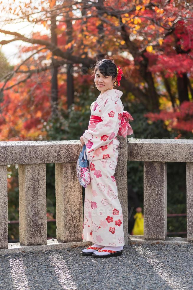 giovane turista che indossa un kimono godendo con foglie colorate nel tempio di kiyomizu dera, kyoto, giappone. ragazza asiatica con acconciatura in abiti tradizionali giapponesi nella stagione del fogliame autunnale foto