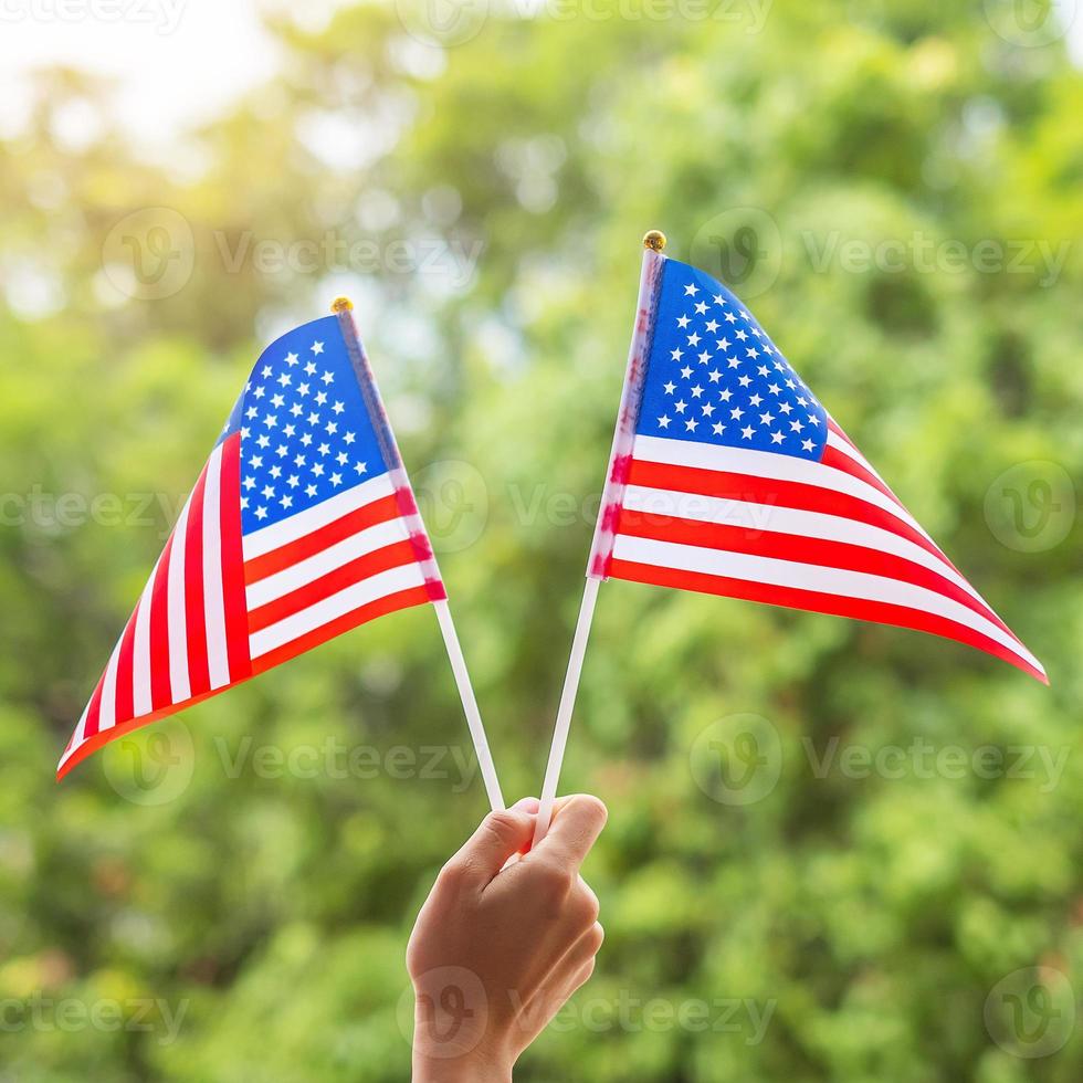 mano che tiene la bandiera degli stati uniti d'america su sfondo verde. festa degli Stati Uniti dei veterani, memoriale, indipendenza e concetto di festa del lavoro foto
