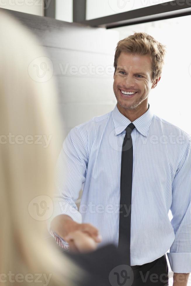 sorridenti uomini d'affari si stringono la mano foto