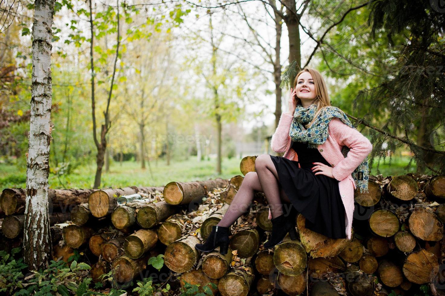 giovane ragazza bionda al cappotto rosa poste su uno sfondo di ceppi di legno. foto