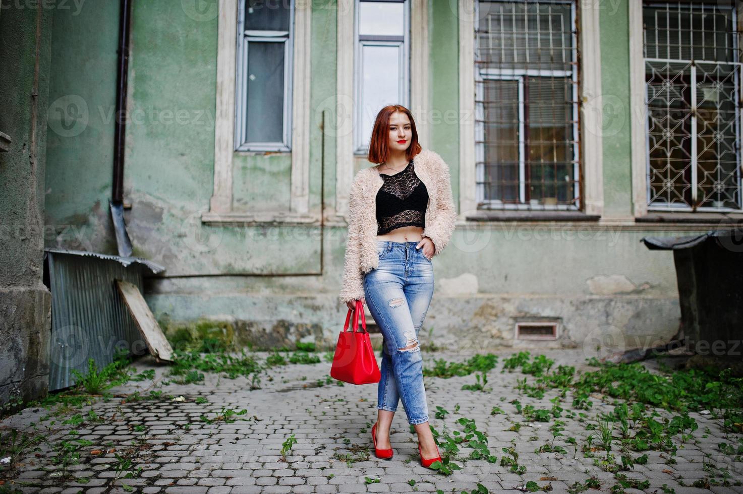 ragazza dai capelli rossi con borsa rossa poste in strada della città. foto