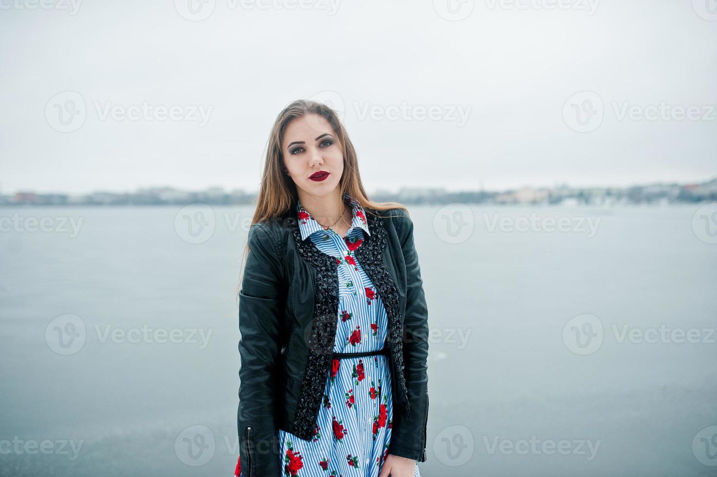 ragazza alla moda in giacca di pelle al giorno d'inverno contro il lago ghiacciato. foto