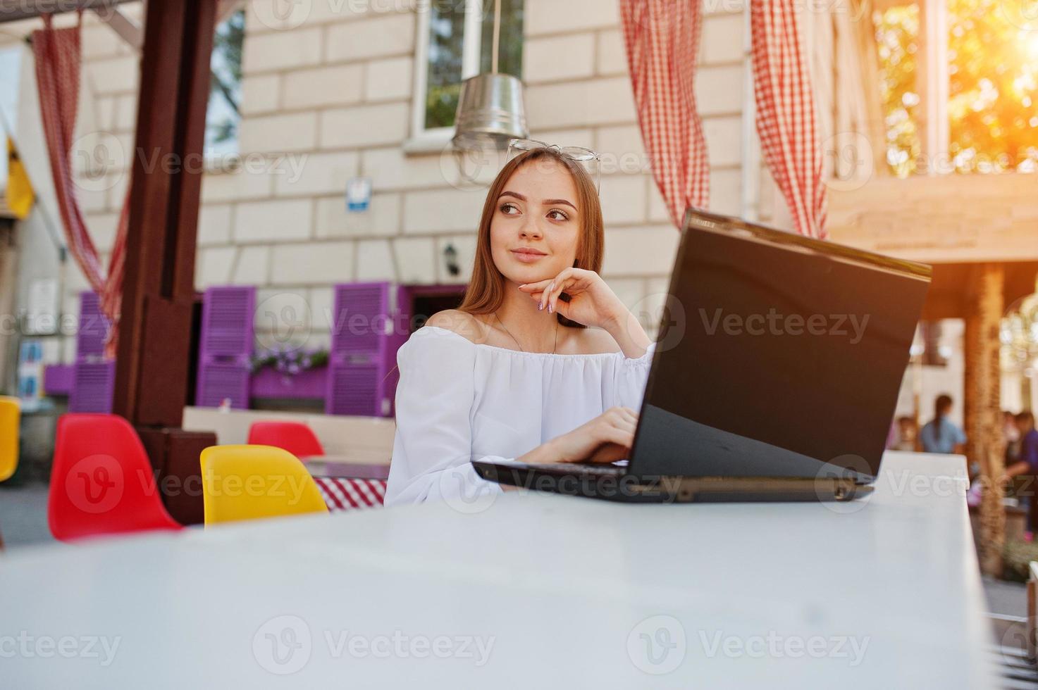 ritratto di una forte imprenditrice di successo indipendente che indossa abiti casual intelligenti e occhiali che lavorano su un laptop in un caffè. foto