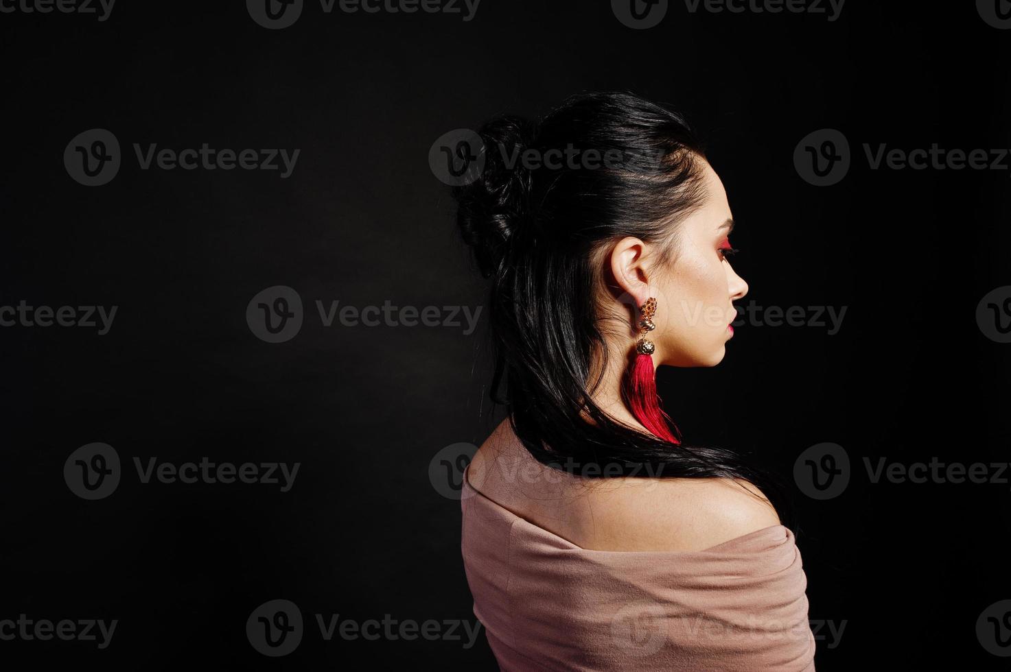 ritratto in studio di ragazza bruna capelli indietro su sfondo nero. foto