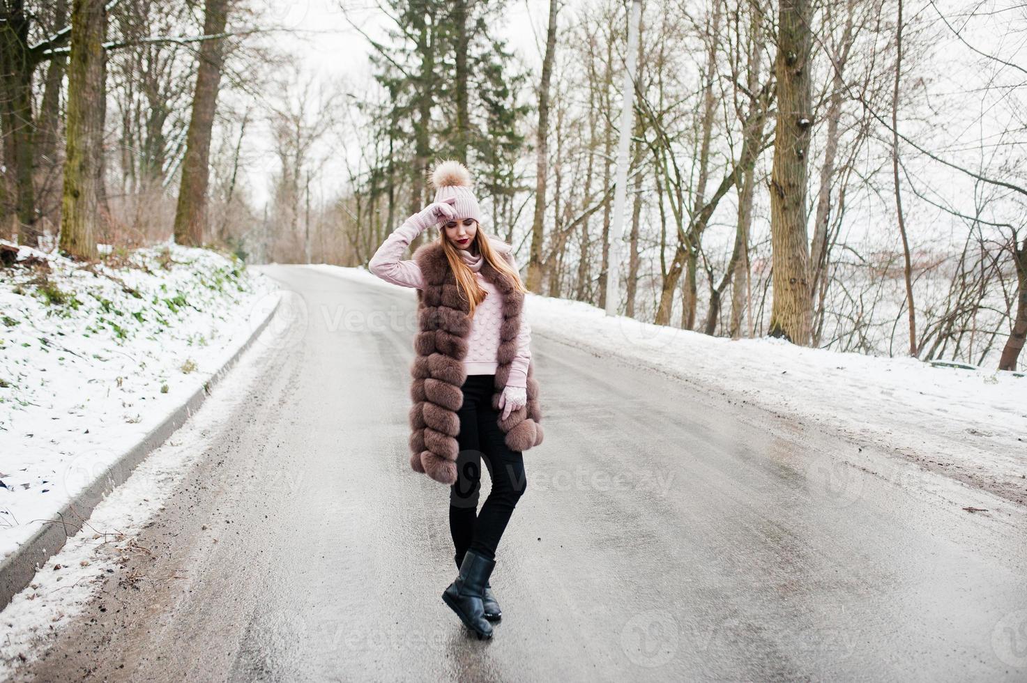 ragazza alla moda in pelliccia e copricapo al giorno d'inverno sulla strada. foto