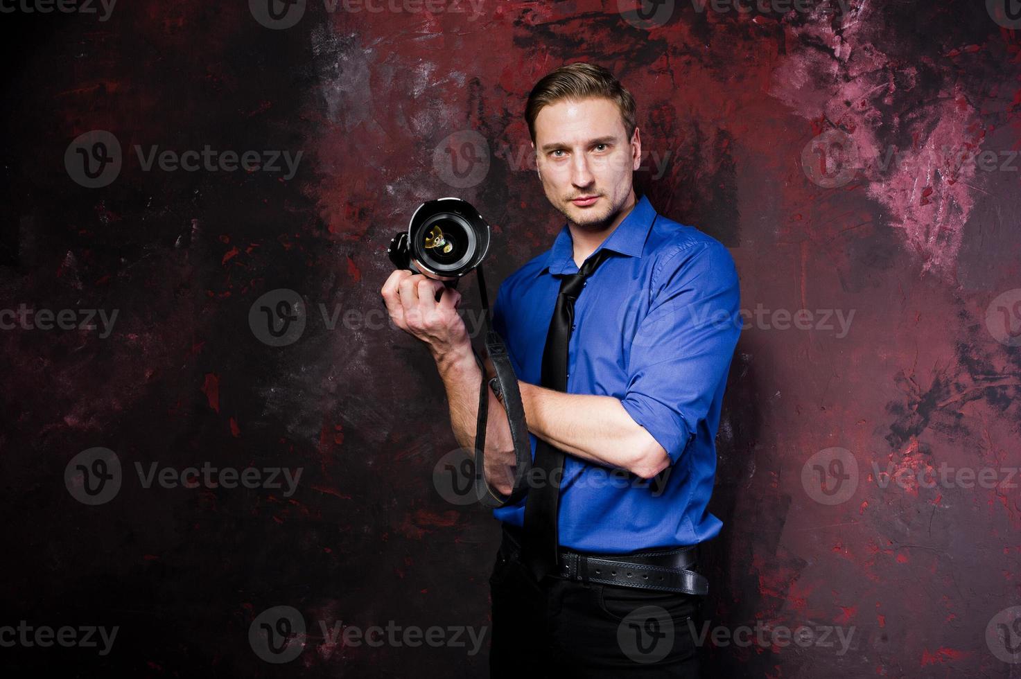 ritratto in studio di elegante fotografo professionista uomo con fotocamera, indossare su camicia blu e cravatta. foto