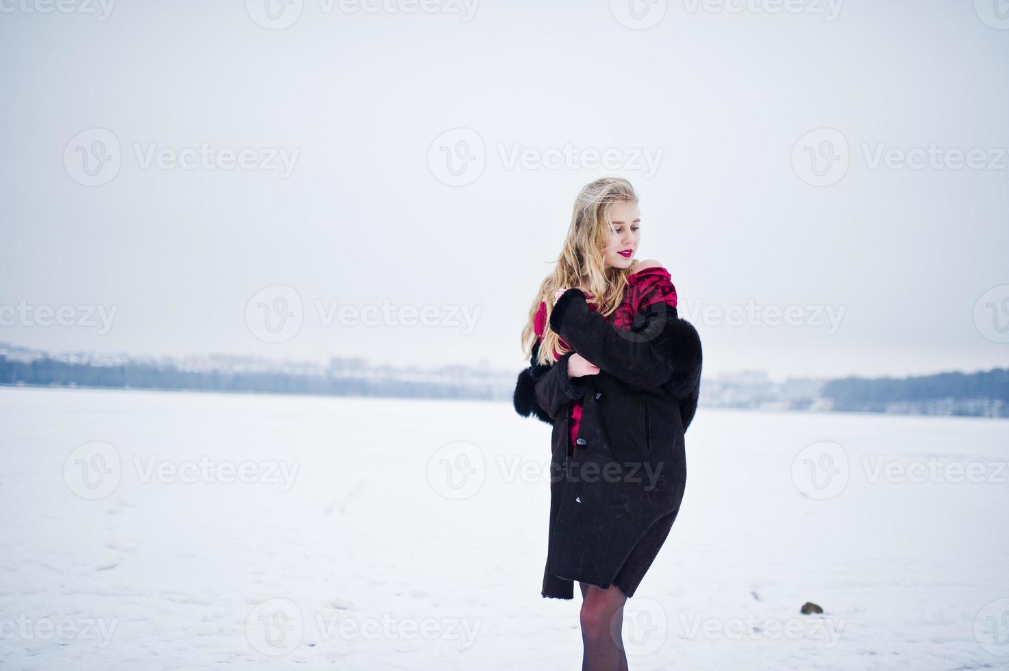 eleganza bionda ragazza in pelliccia e abito da sera rosso poste in inverno nevoso giorno. foto