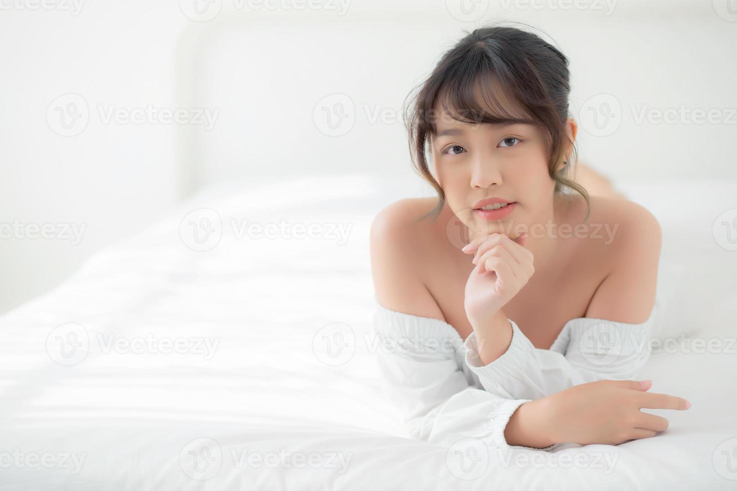 bel ritratto giovane donna asiatica sdraiata e sorriso mentre si sveglia con l'alba al mattino, bellezza ragazza carina felice e allegra che riposa sul letto in camera da letto, stile di vita e relax concetto. foto