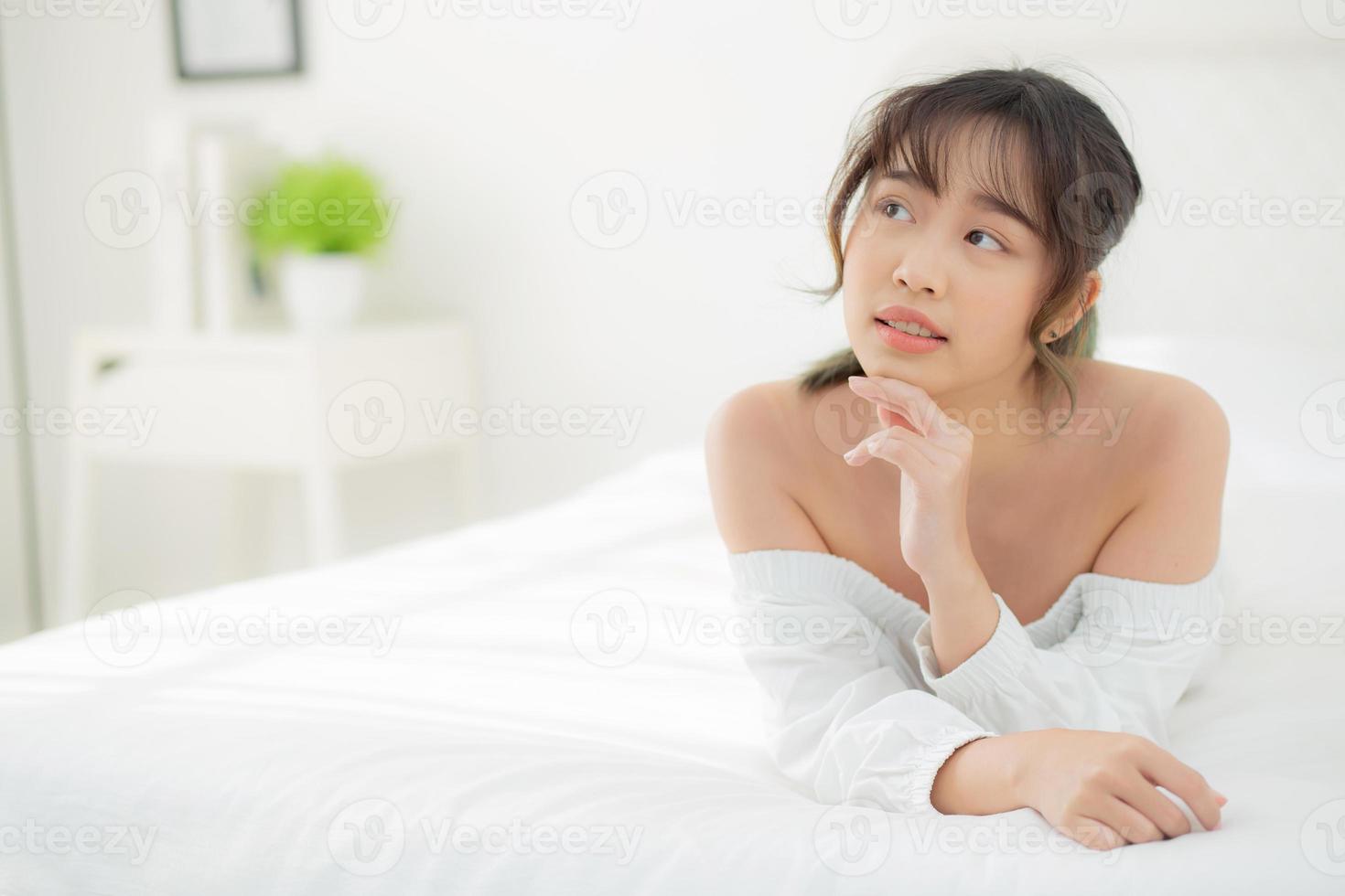 bel ritratto giovane donna asiatica sdraiata e sorriso mentre si sveglia con l'alba al mattino, bellezza ragazza carina felice e allegra che riposa sul letto in camera da letto, stile di vita e relax concetto. foto