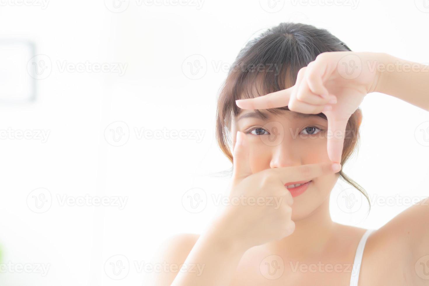 bella giovane donna asiatica cura della pelle degli occhi e cornice gestuale con la mano per la visione, bellezza asia ragazza viso cosmetici e trucco per la salute, vista della donna per il benessere con freschezza. foto