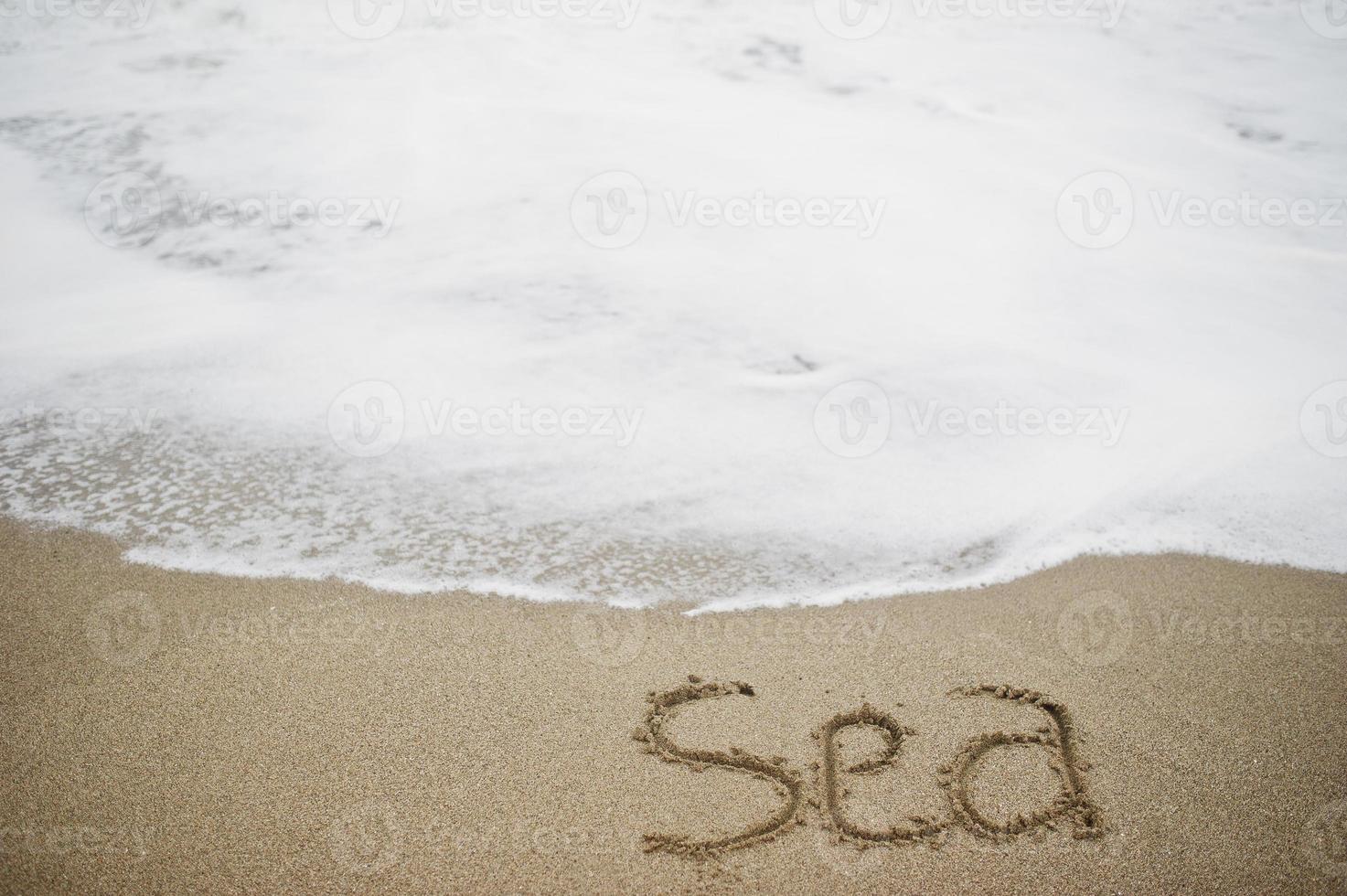 foto ravvicinata del mare con iscrizione di sabbia dalle onde spumose.