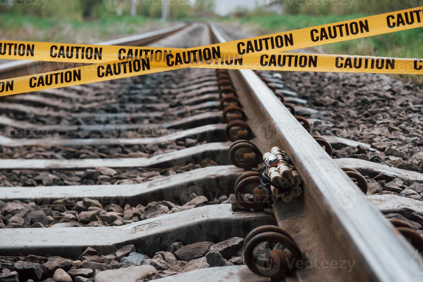 essere consapevoli. pericoloso esplosivo giacente sulla ferrovia. nastro di avvertenza giallo davanti foto