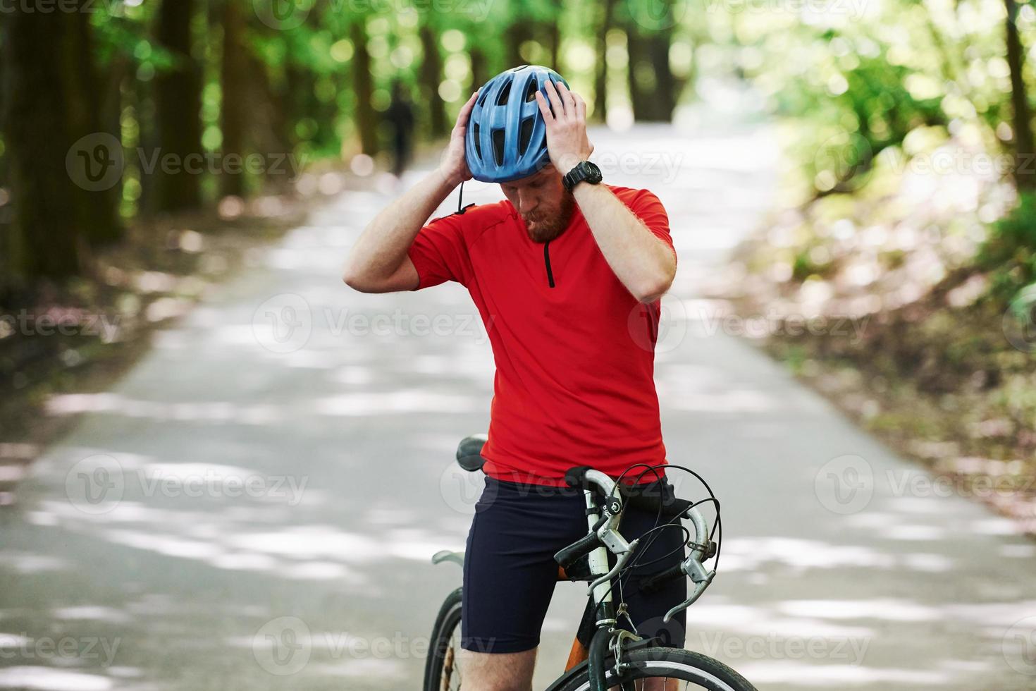 andiamo. il ciclista in bicicletta è sulla strada asfaltata nella foresta in una giornata di sole foto