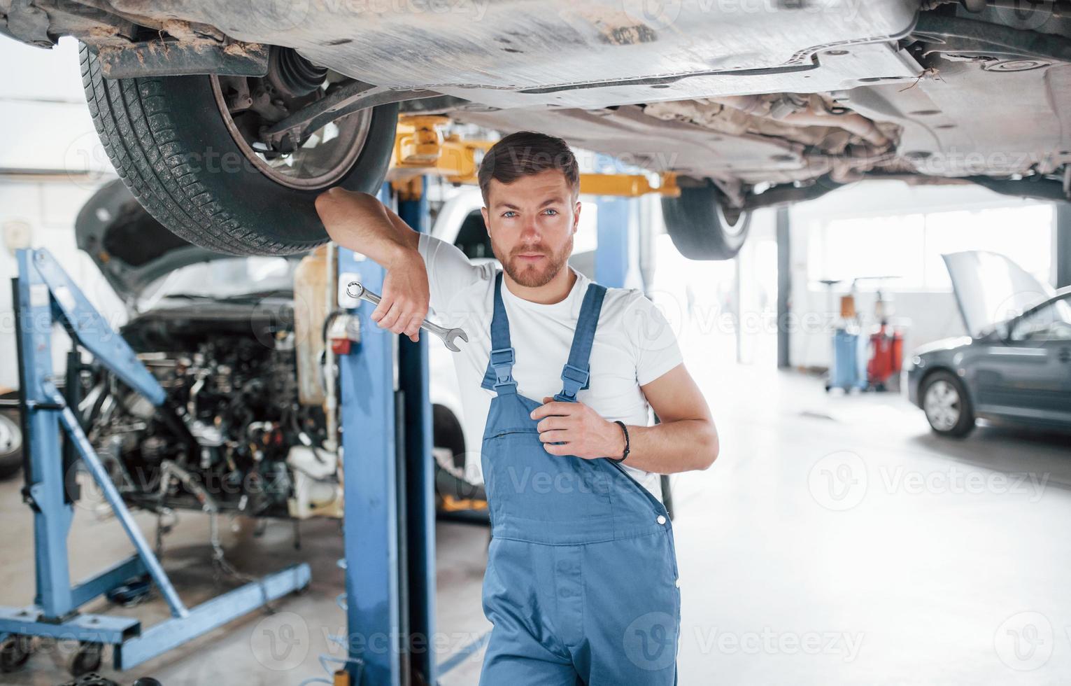 la tua macchina è in buone mani. dipendente in uniforme di colore blu lavora nel salone dell'automobile foto