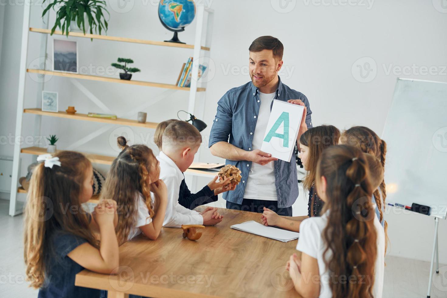 mostrando una lettera. gruppo di bambini studenti in classe a scuola con l'insegnante foto