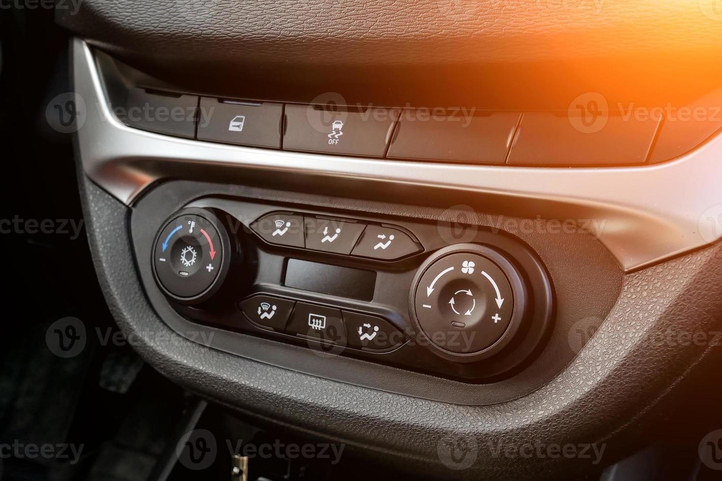 la consolle di comando centrale sul pannello interno vettura primo piano con climatizzatore e impianto audio e foro per cd e pulsante di emergenza in grigio e nero. foto