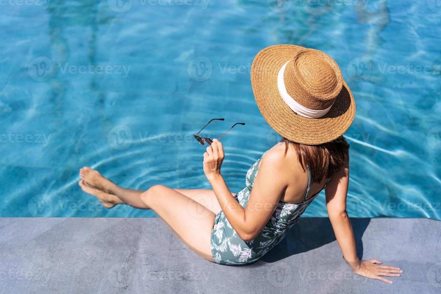 viaggiatore della giovane donna che si rilassa e si diverte in una piscina tropicale del resort mentre viaggia per le vacanze estive, concetto di viaggio foto