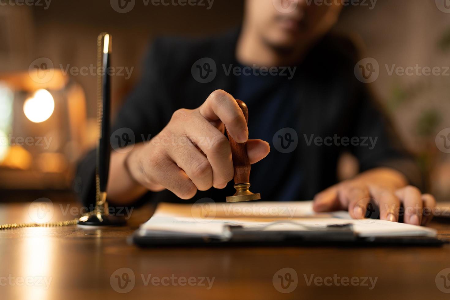 primo piano della mano di una persona che timbra con timbro approvato sul documento di certificato carta pubblica alla scrivania, notaio o uomini d'affari lavorano da casa, isolati per la protezione del coronavirus covid-19 foto