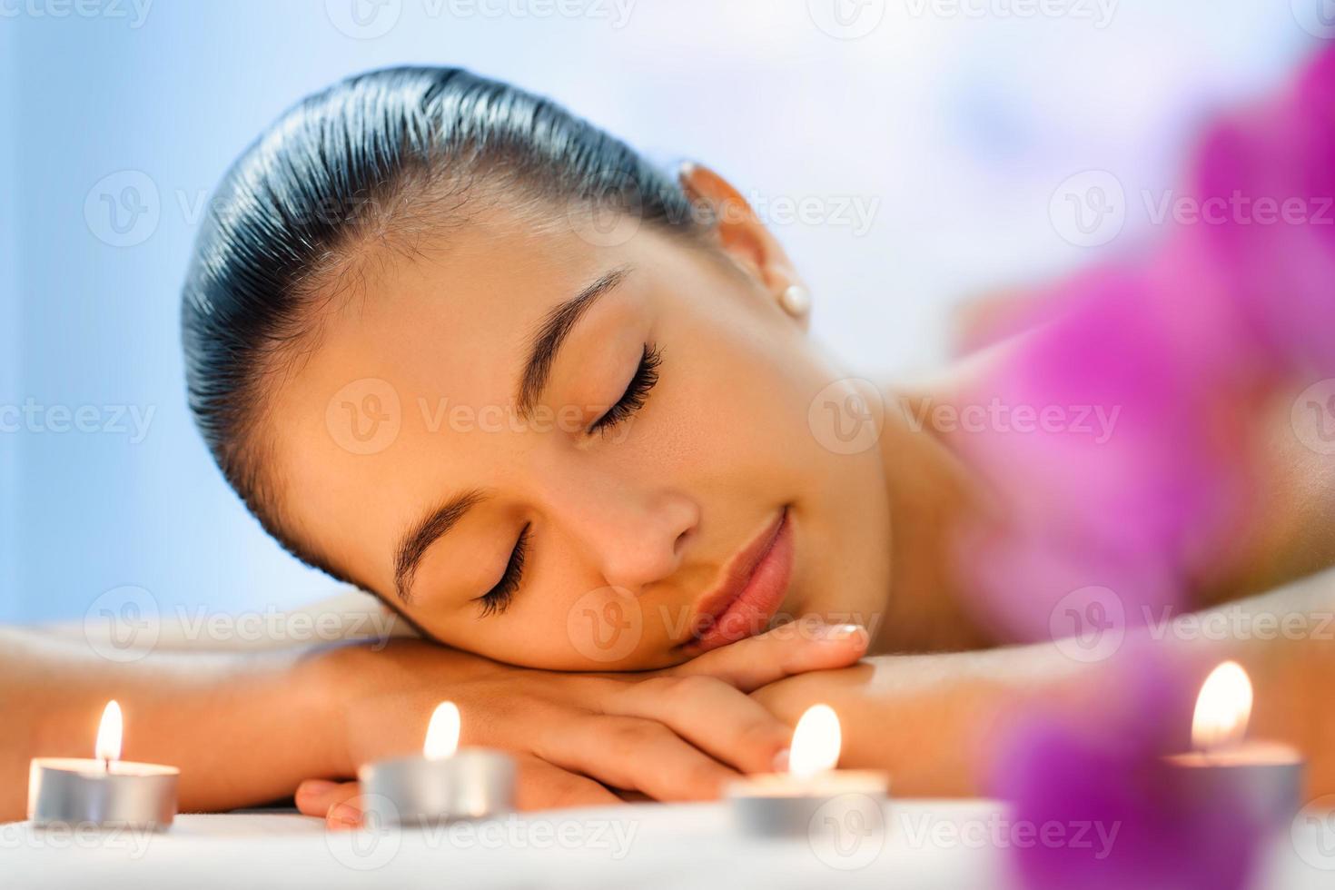 giovane donna che si distende alla luce fioca della candela dopo il massaggio. foto