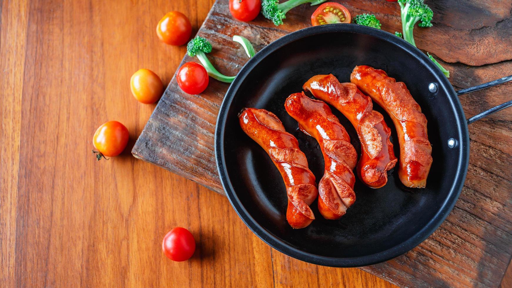 salsicce fritte in padella con pomodori e broccoli foto