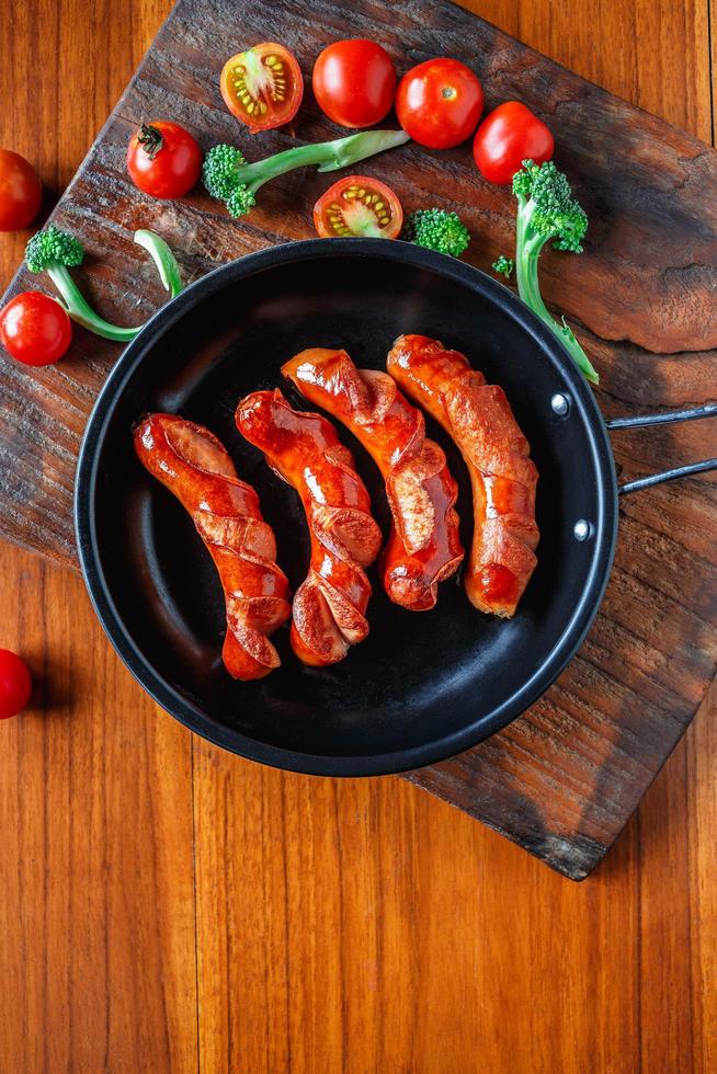 salsicce fritte in padella con pomodori e broccoli foto