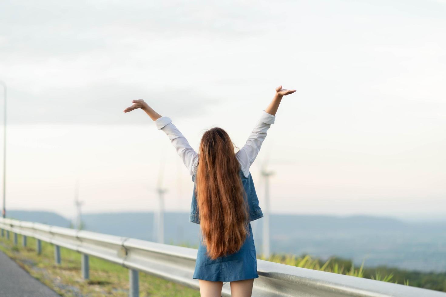 donna felice che si gode la vita nel campo con la foresta. bellezza della natura, cielo nuvoloso blu e campo colorato con la natura. stile di vita all'aperto. concetto di libertà. foto