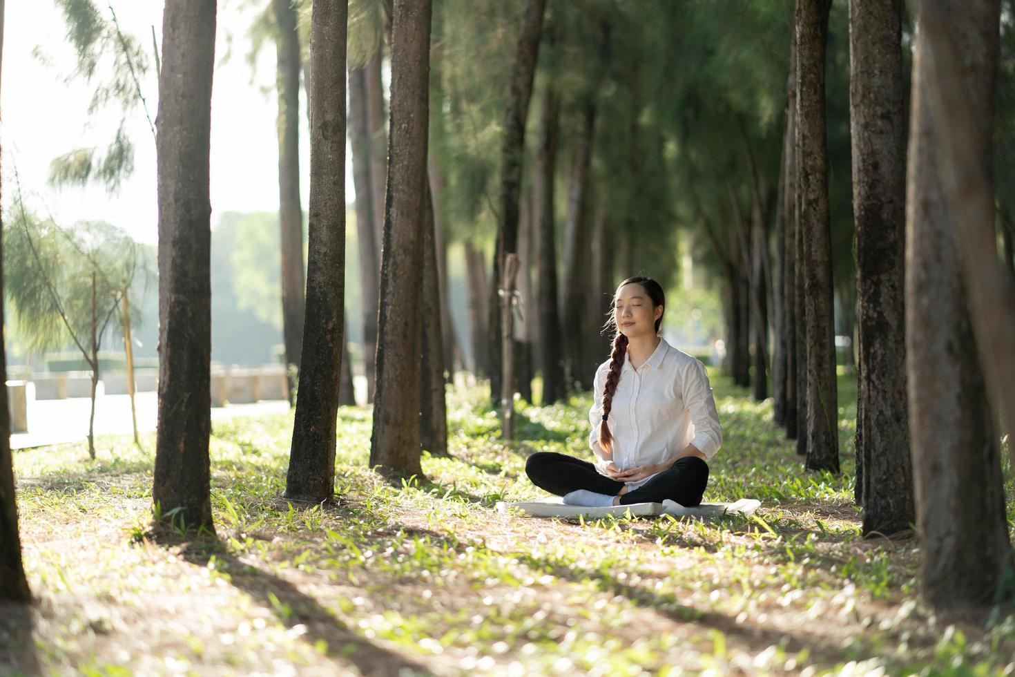 la giovane donna asiatica che pratica medita al parco verde, concetto di stile di vita sano. foto