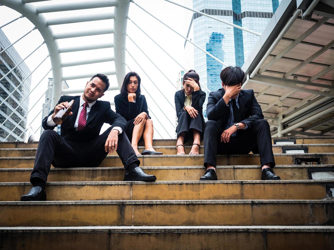 gruppo di uomini e donne d'affari seduti nel parco all'aperto e stressati a causa del fallimento del lavoro d'affari foto