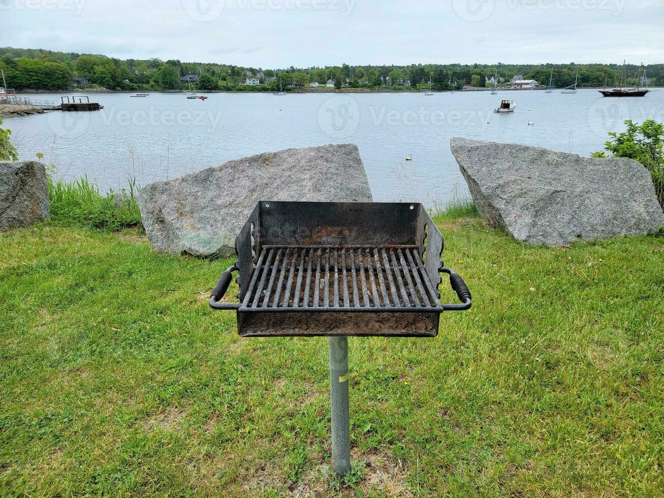 barbecue in erba vicino al lago con barche e rocce foto