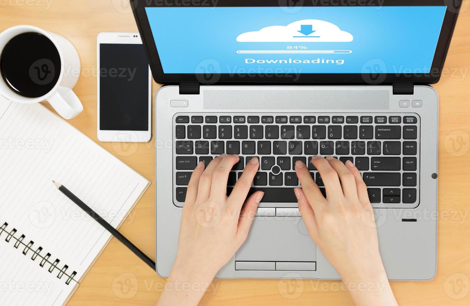 vista dall'alto dell'area di lavoro aziendale su download cloud, notebook, tazza di caffè e mani femminili che digitano sulla tastiera foto