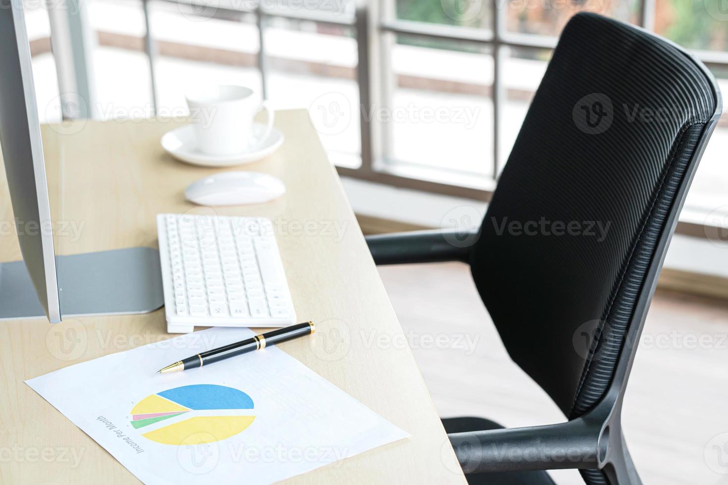 concetto di business e posto di lavoro. tazza di caffè caldo sulla scrivania con la tastiera del computer e grafici di documenti nella sala di lavoro dell'ufficio. foto
