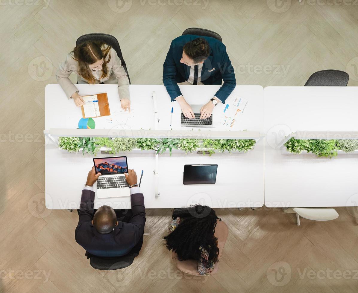 vista dall'alto del team di uomini d'affari che lavora a un nuovo progetto di avvio in un ufficio moderno. gruppo di colleghi di lavoro multietnici seduti insieme a fare brainstorming, pianificare e parlare della strategia di avvio. foto