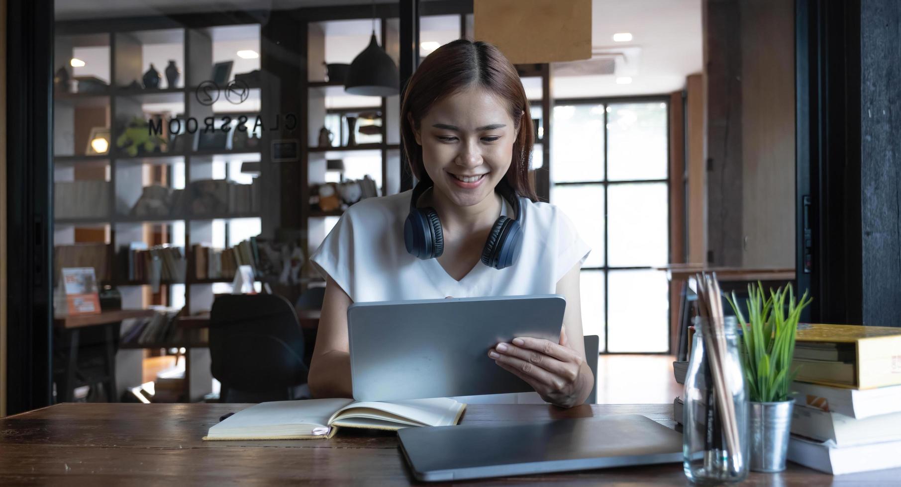 sorridente giovane donna asiatica che utilizza l'auricolare guardando lo schermo del laptop ascolta e impara corsi online. felice donna d'affari cinese con le cuffie videochiamata per il servizio clienti foto