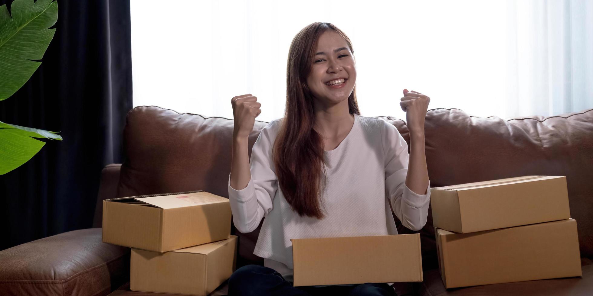 felice giovane donna asiatica imprenditrice, sorriso per il successo delle vendite dopo aver controllato l'ordine dal negozio di shopping online a casa, concetto di attività commerciale online ed e-commerce foto