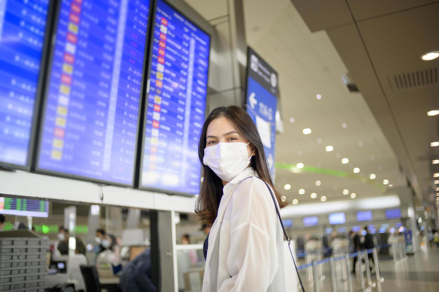 una donna viaggiatrice indossa una maschera protettiva nell'aeroporto internazionale, viaggia sotto la pandemia covid-19, viaggi di sicurezza, protocollo di allontanamento sociale, nuovo concetto di viaggio normale. foto