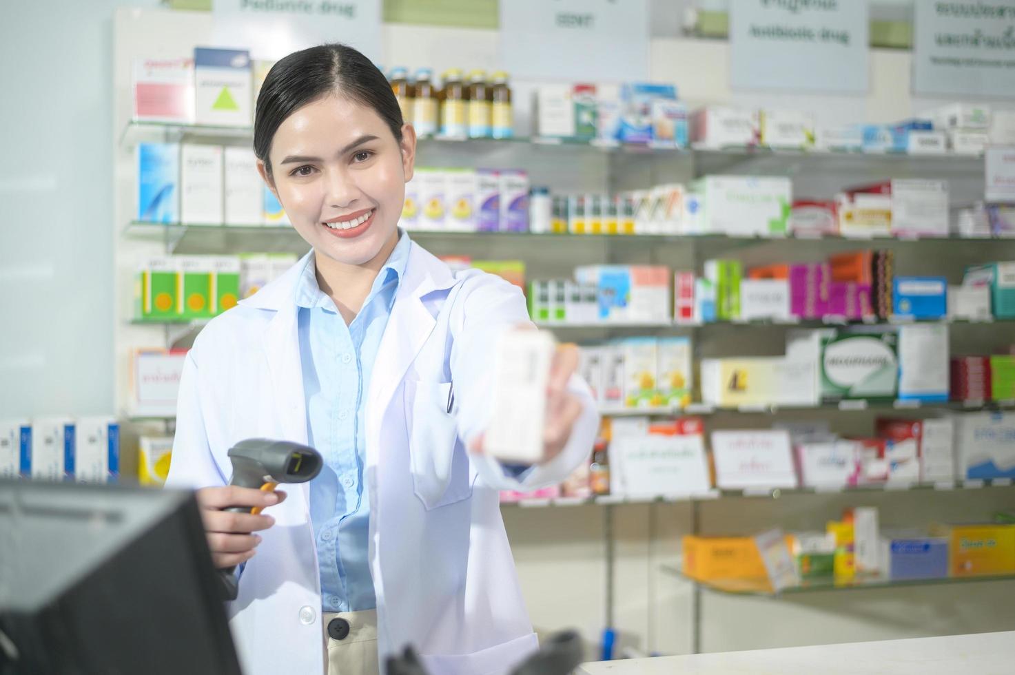 farmacista femminile che scansiona il codice a barre su una scatola di medicinali in una moderna farmacia. foto