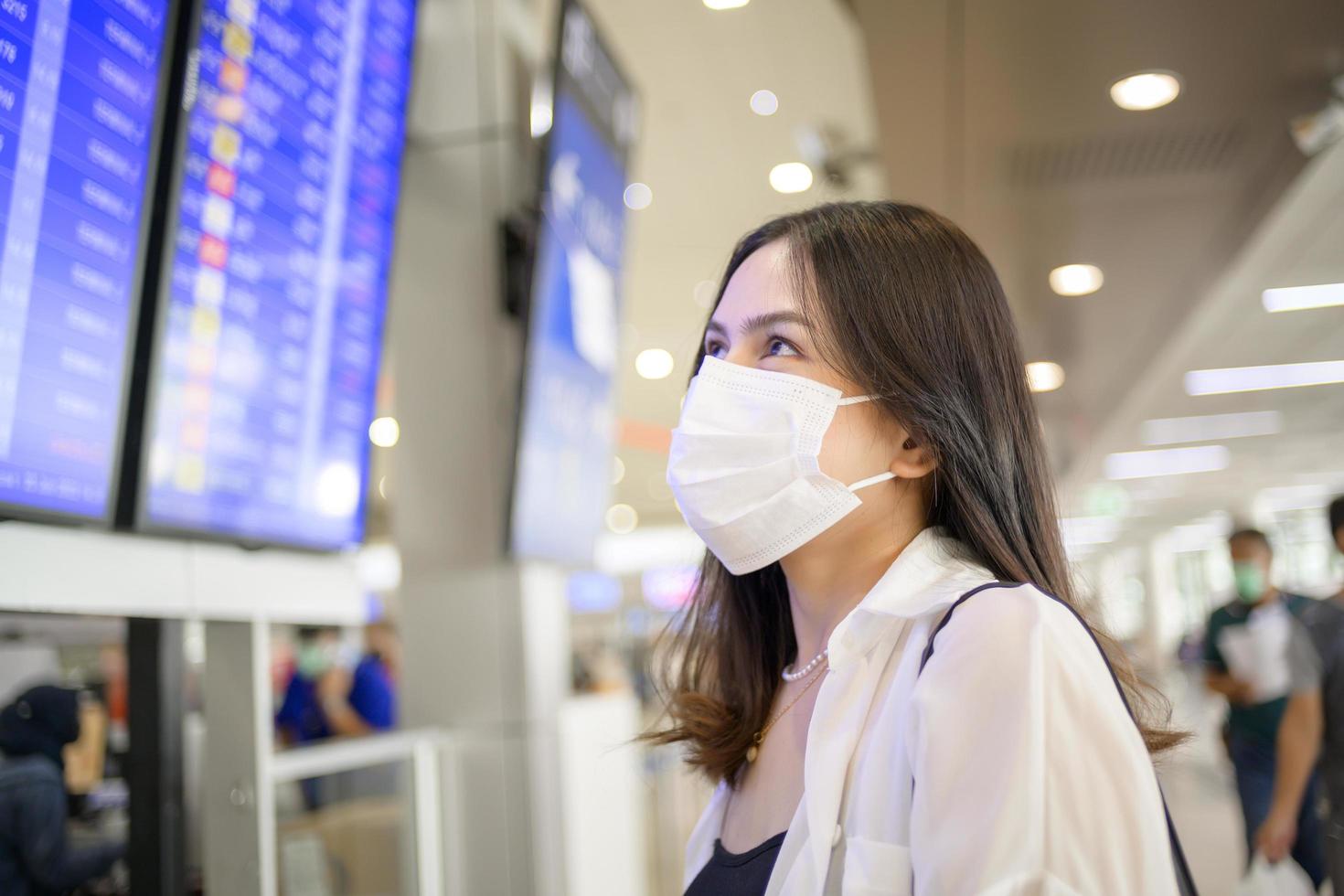 una donna viaggiatrice indossa una maschera protettiva nell'aeroporto internazionale, viaggia sotto la pandemia covid-19, viaggi di sicurezza, protocollo di allontanamento sociale, nuovo concetto di viaggio normale. foto