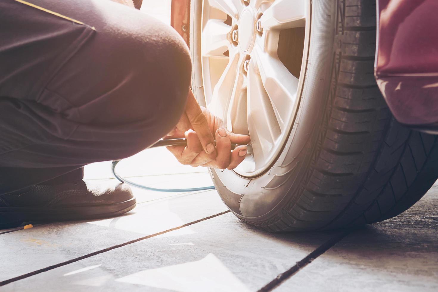 il tecnico è gonfiare il pneumatico dell'auto - concetto di sicurezza del trasporto del servizio di manutenzione dell'auto foto