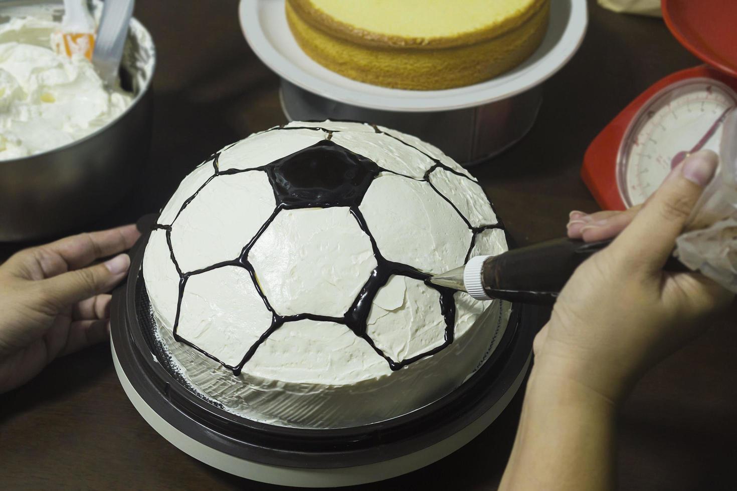 signora che fa la torta, decorazione del modello di calcio foto