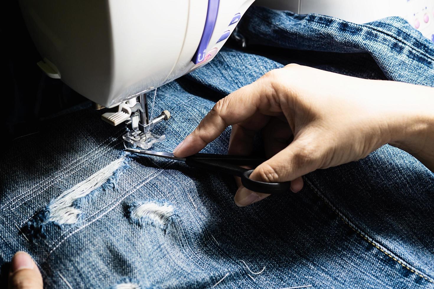 donna che fa patchwork di jeans utilizzando la macchina da cucire - concetto di cucito fai da te per la casa foto