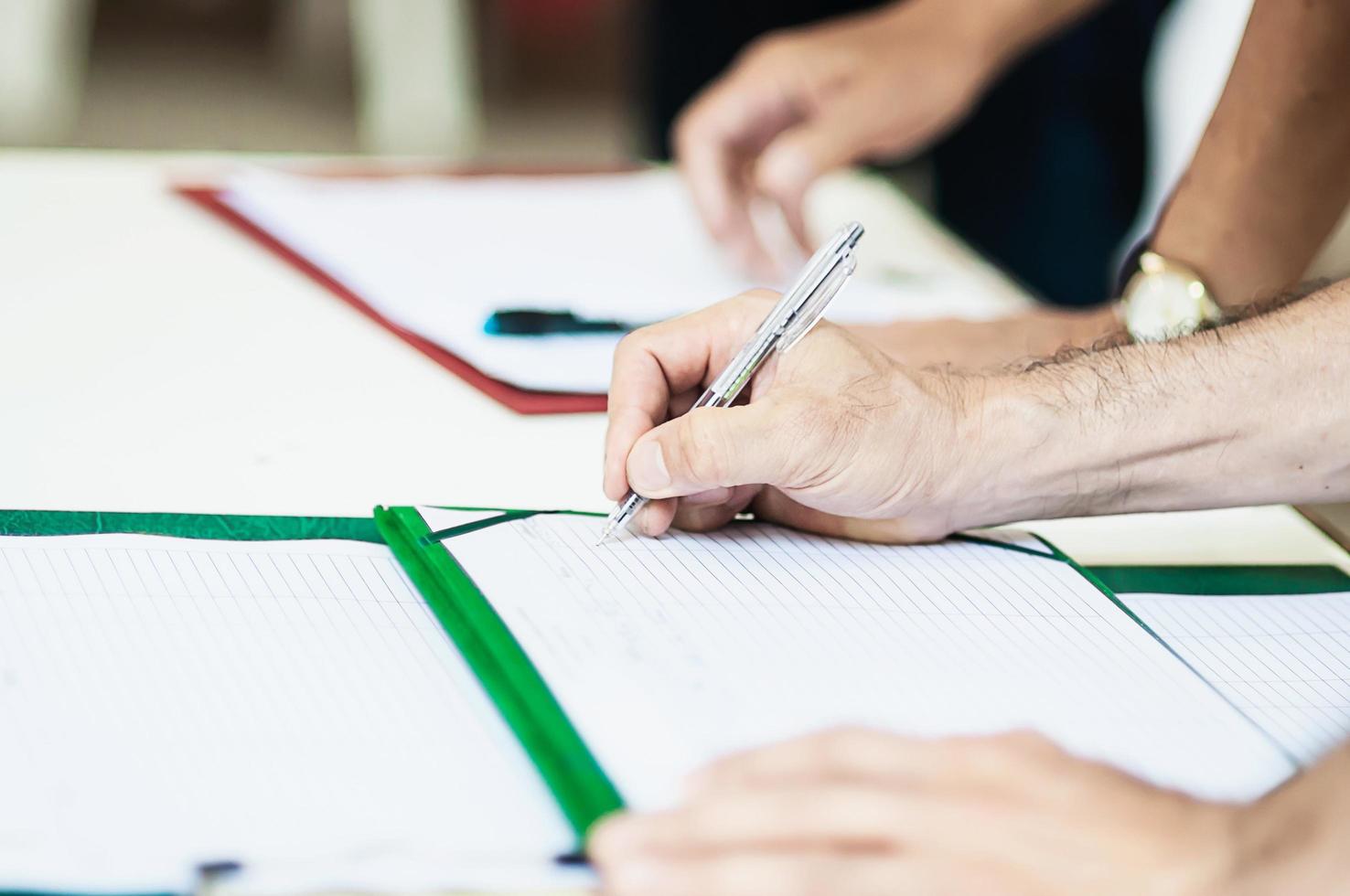 primo piano della mano delle persone con la penna al punto di registrazione - persone in riunione concetto di evento aziendale di lavoro foto