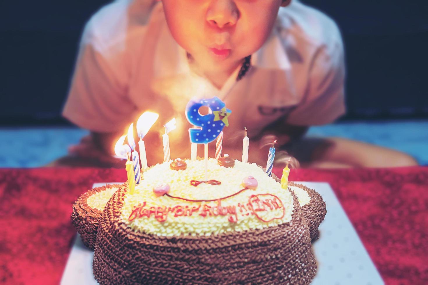 il bambino sta soffiando allegramente le candeline sulla sua torta di compleanno - concetto di celebrazione della festa di compleanno felice e gioiosa foto