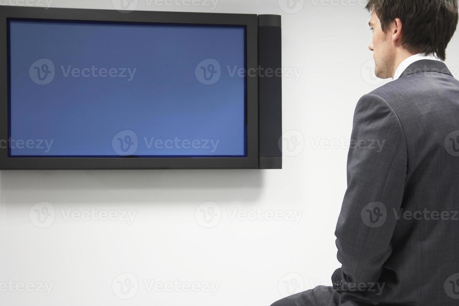 uomo d'affari guardando la televisione a schermo piatto foto