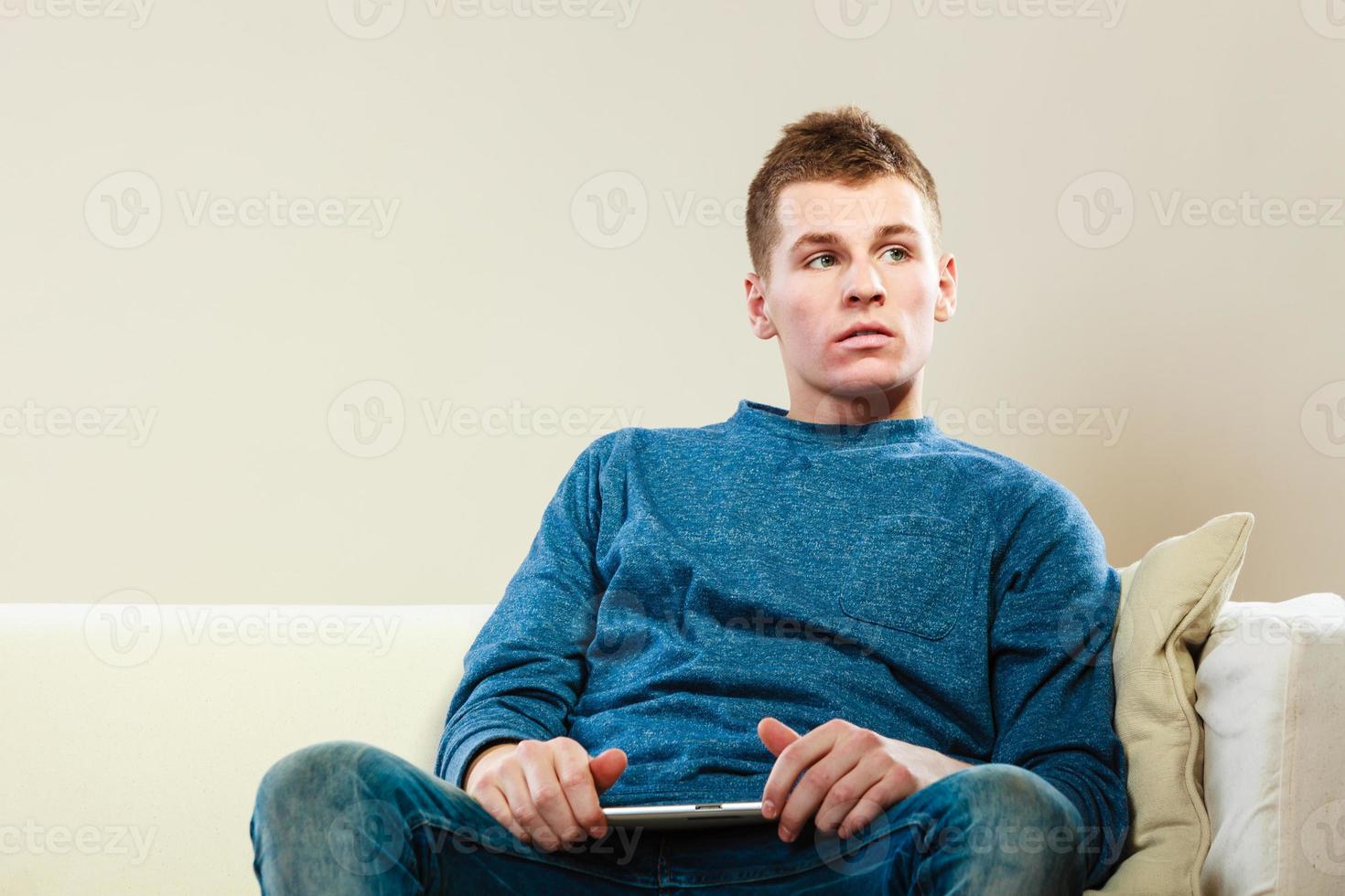 giovane con tavoletta digitale seduto sul divano foto