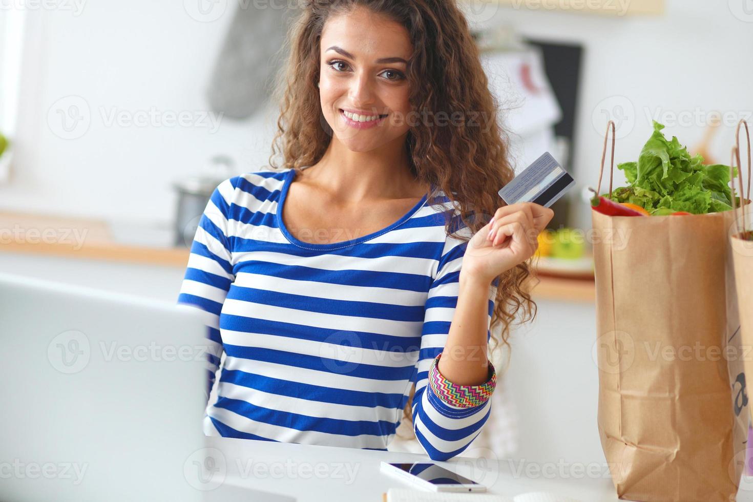 acquisto online sorridente della donna facendo uso del computer e della carta di credito dentro foto
