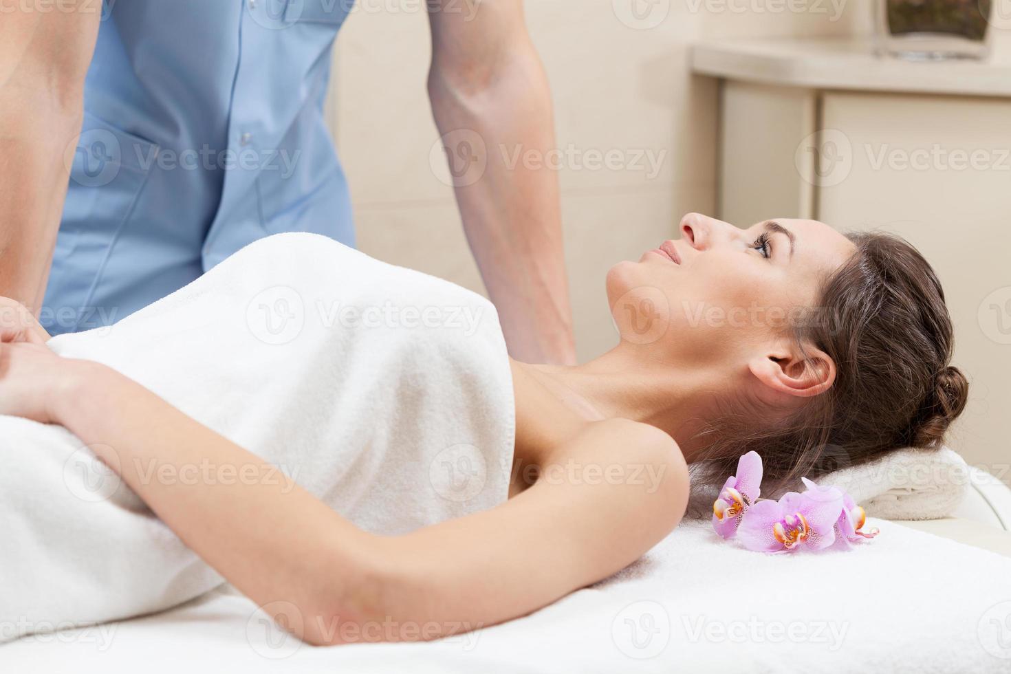 donna avvolta in un asciugamano bianco sdraiato sul lettino da massaggio foto