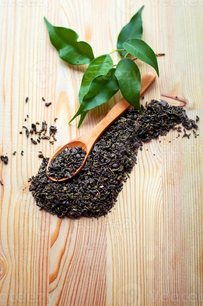 tè verde in cucchiaio di legno e foglie di tè foto