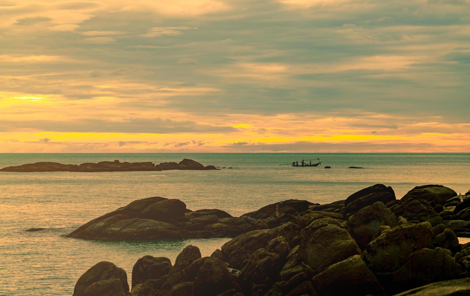 bellissima spiaggia di pietra al mattino con il cielo dorato dell'alba. pescatore in barca a coda lunga con cultura popolare della pesca. scena pacifica e tranquilla. mare calmo al mattino. vista sul mare con orizzonte. foto